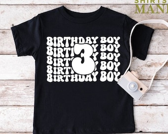 May include: Black t-shirt with white text that says "Birthday Boy" repeated multiple times. The number "3" is in the center of the shirt in a retro font.
