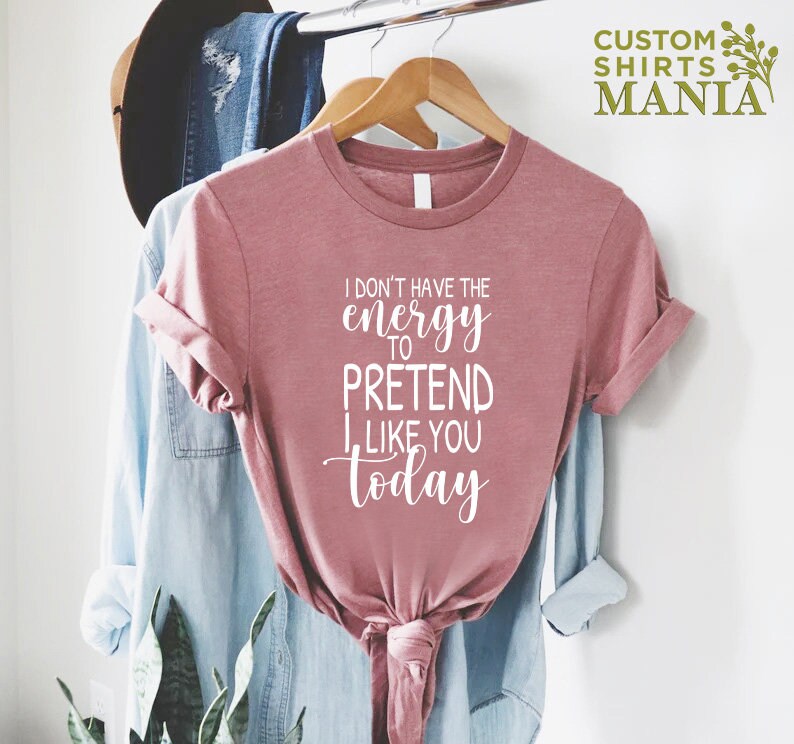 May include: A pink t-shirt with the text "I don't have the energy to pretend I like you today" in white lettering.