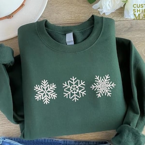 a green sweater with white snowflakes on it
