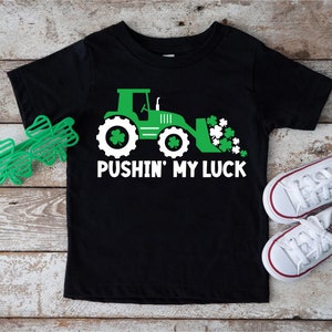 May include: Black t-shirt with a green tractor and shamrocks, and the text "Pushin' My Luck".
