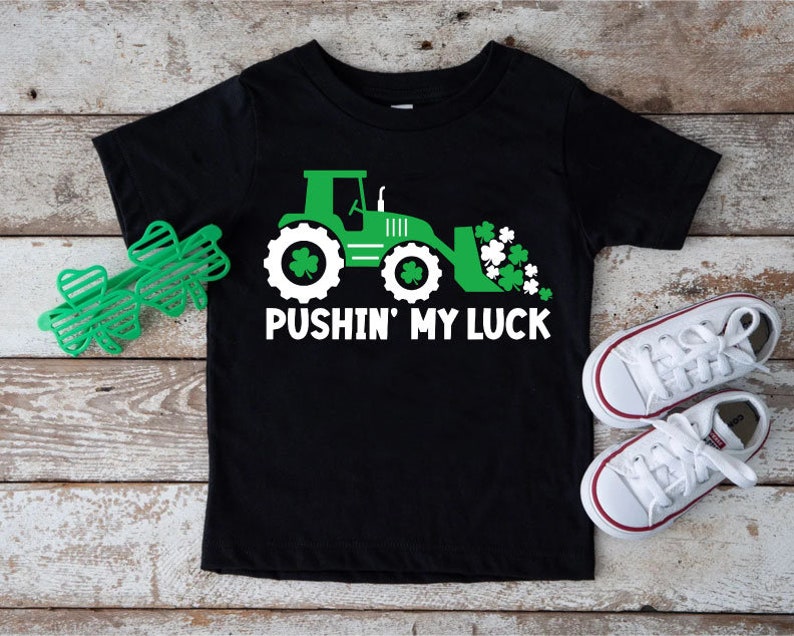 May include: Black t-shirt with a green tractor and shamrocks, and the text "Pushin' My Luck".