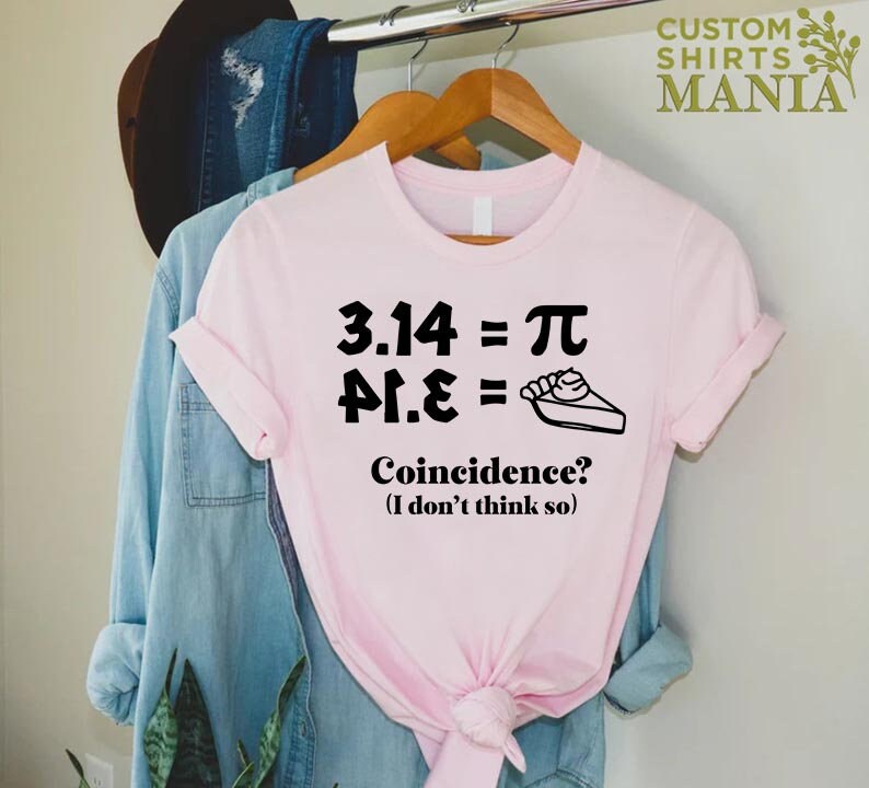 K&ouml;nnte beinhalten: Ein pinkfarbenes T-Shirt mit einer schwarzen Grafik, auf der "3.14 = &pi;, &pi;.14 =  " steht, sowie ein Bild von einem St&uuml;ck Kuchen. Der Text unter der Grafik lautet "Zufall? (Ich glaube nicht)"