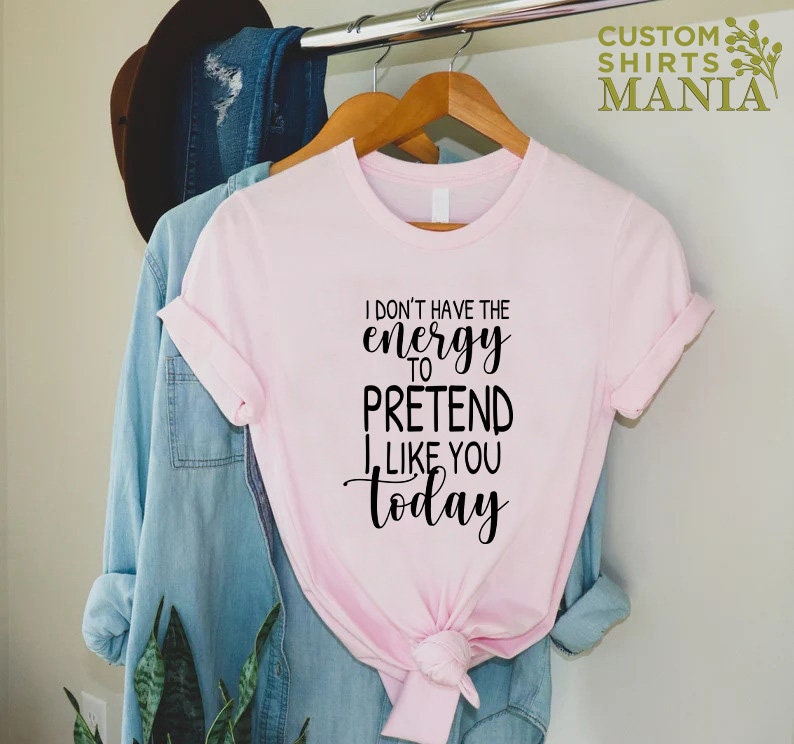May include: Pink t-shirt with black text that reads "I don't have the energy to pretend I like you today."