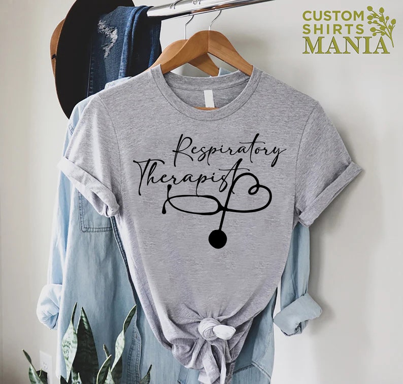 May include: Gray t-shirt with the text "Respiratory Therapist" in black cursive lettering and a stethoscope with a heart design.