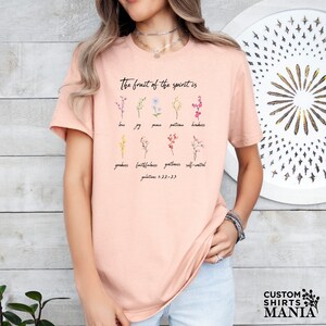 a woman wearing a pink t - shirt with flowers on it