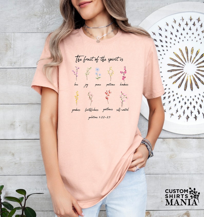 a woman wearing a pink t - shirt with flowers on it
