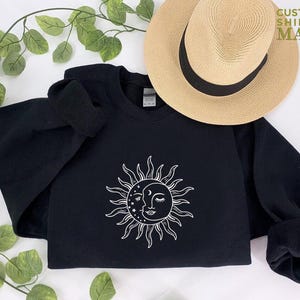 a black sweatshirt with a sun design on it