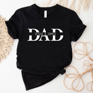 Pu&ograve; includere: Maglietta nera con testo bianco che dice "DAD Olivia & James".