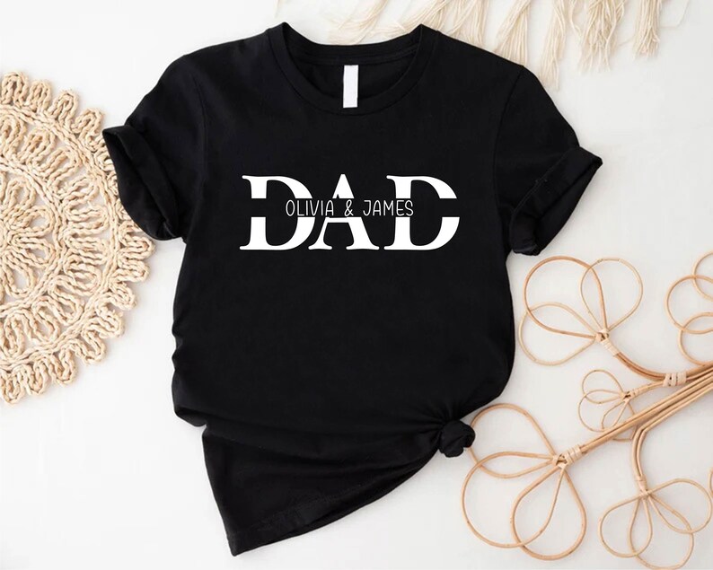 Pu&ograve; includere: Maglietta nera con testo bianco che dice "DAD Olivia & James".