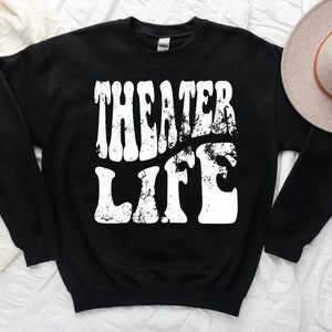 May include: Black sweatshirt with white text that reads "Theater Life" in a retro font.