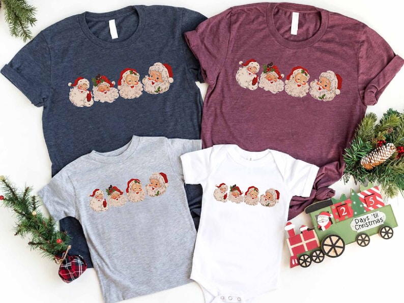 May include: A set of four t-shirts featuring a vintage-style illustration of Santa Claus's faces. The shirts are in navy blue, burgundy, gray, and white.