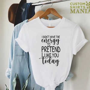 May include: White t-shirt with black text that reads "I don't have the energy to pretend I like you today".