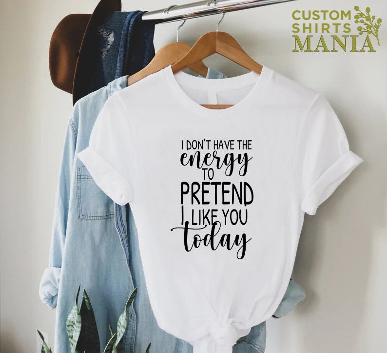 May include: White t-shirt with black text that reads "I don't have the energy to pretend I like you today".