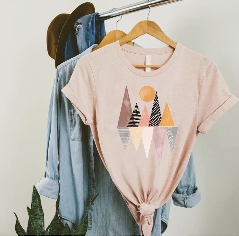 a t - shirt hanging on a rack next to a pair of jeans