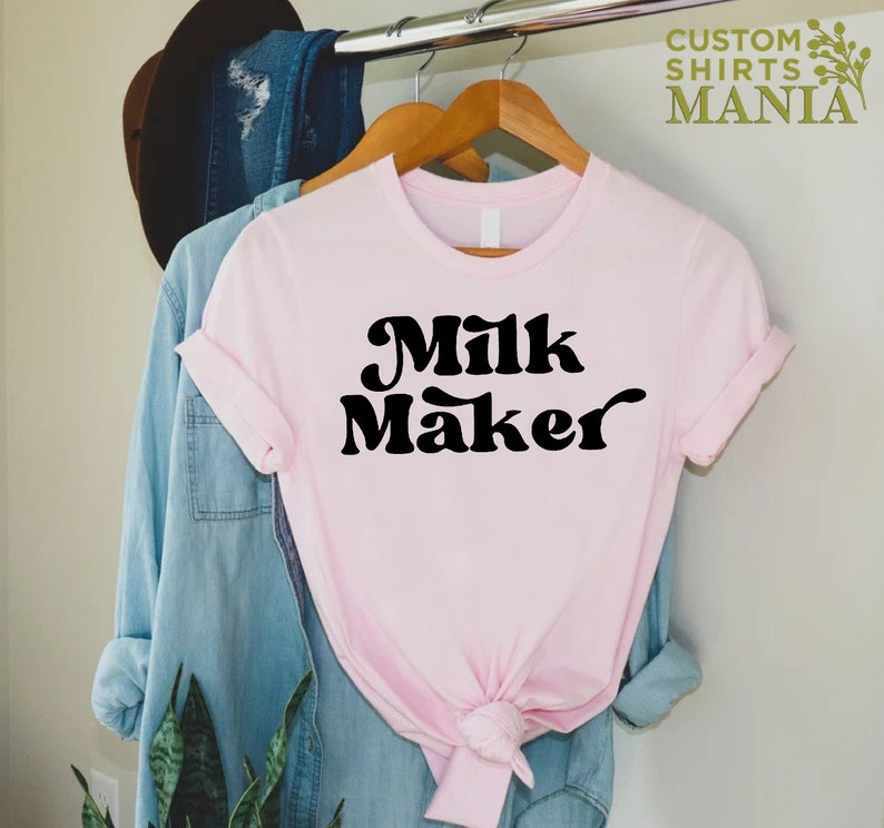 May include: A pink t-shirt with the text "Milk Maker" in black retro-style lettering.