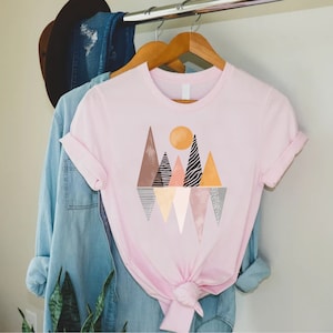 a pink t - shirt with mountains and trees on it