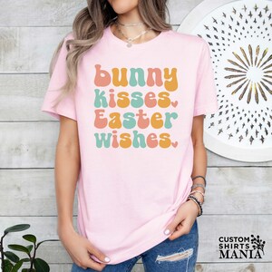 a woman wearing a pink t - shirt that says bunny kisses easter wishes