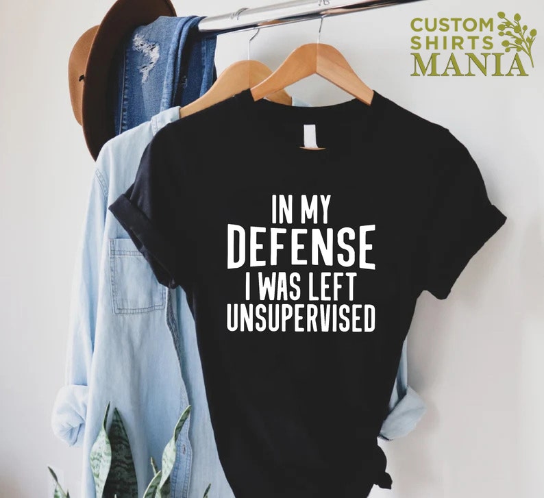 May include: Black t-shirt with white text that reads "In my defense I was left unsupervised".