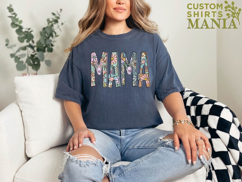 a woman sitting on a couch wearing a shirt that says mama