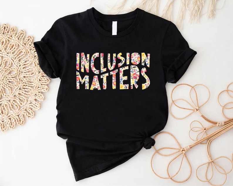 Puede incluir: Camiseta negra con el texto "Inclusion Matters" en letras blancas delineadas con un patr&oacute;n floral.