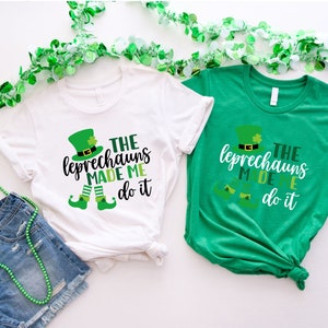 May include: Two white and green t-shirts with a leprechaun graphic and the text "The Leprechauns Made Me Do It".