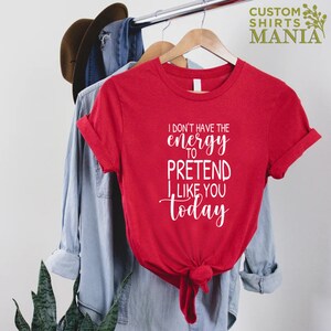 May include: Red t-shirt with white text that reads "I don't have the energy to pretend I like you today".