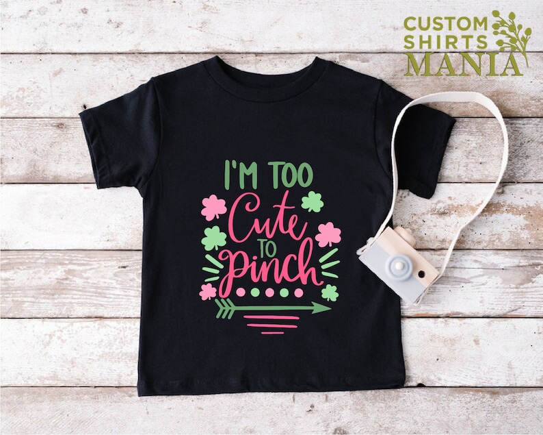 May include: Black t-shirt with a pink and green graphic that says "I'm Too Cute To Pinch".