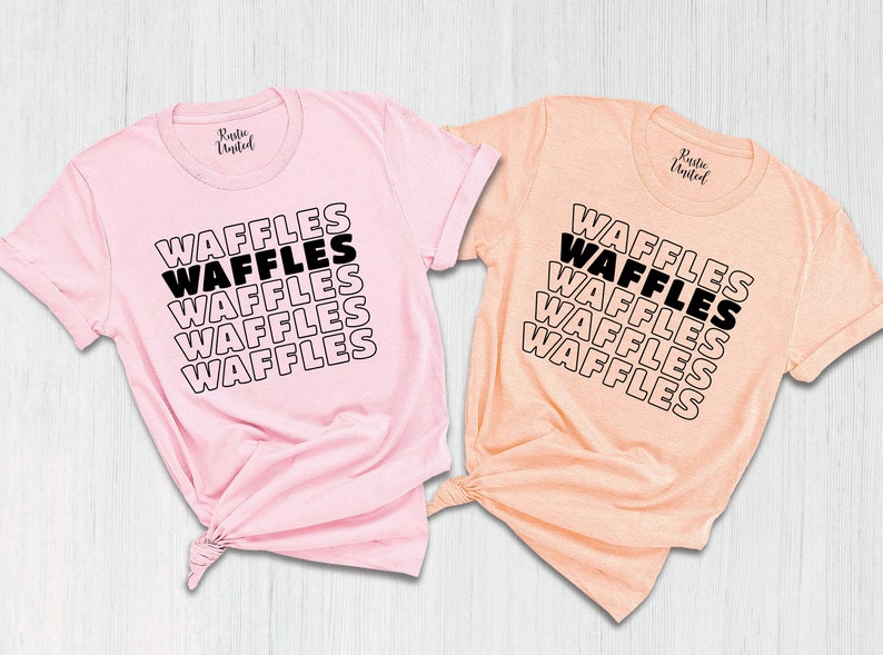 Może przedstawiać: Dwie koszulki z napisem "WAFFLES" powt&oacute;rzonym pięć razy w układzie piętrowym. Koszulki są r&oacute;żowe i brzoskwiniowe.