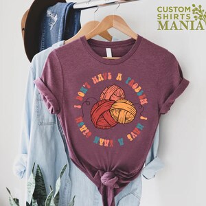 May include: A maroon t-shirt with a graphic of yarn balls and the text "I don't have a problem I have a yarn stash".