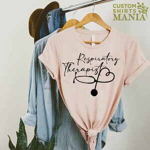 May include: A pink t-shirt with the text "Respiratory Therapist" and a stethoscope with a heart design.