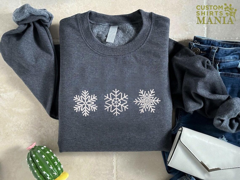 a sweater with snowflakes on it next to a cactus