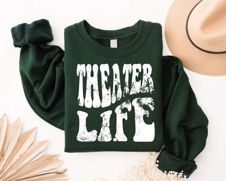 May include: A dark green sweatshirt with the text "Theater Life" in white, distressed lettering.