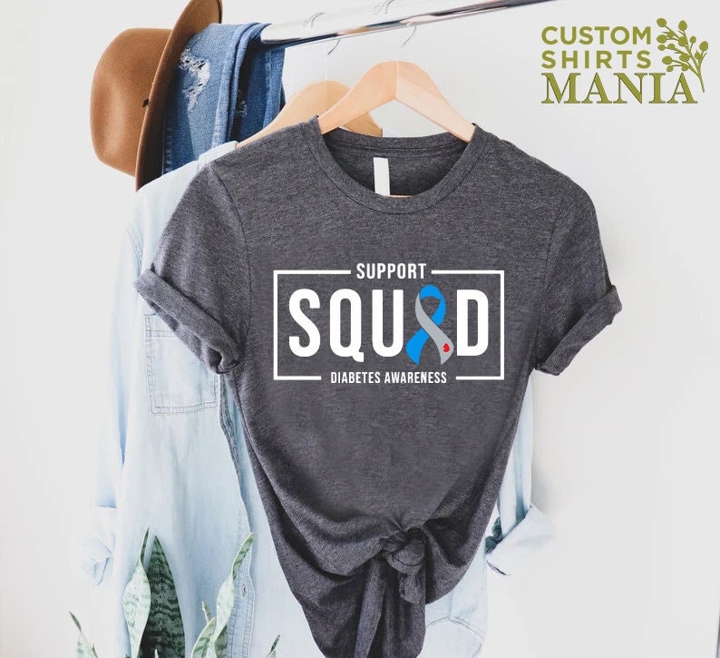 May include: Gray t-shirt with a white square that says "Support Squad" with a blue ribbon and the words "Diabetes Awareness" underneath.