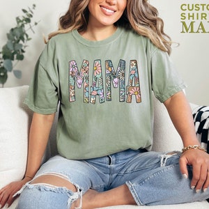 a woman sitting on a couch wearing a shirt that says mama