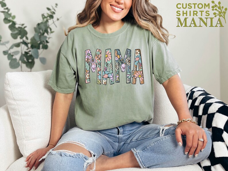 a woman sitting on a couch wearing a shirt that says mama