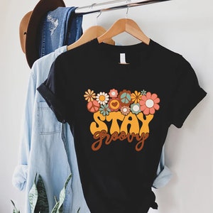 May include: Black t-shirt with a retro-style graphic of flowers and the text "Stay Groovy".