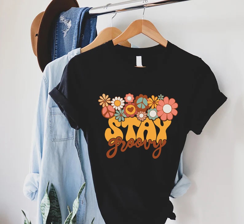 May include: Black t-shirt with a retro-style graphic of flowers and the text "Stay Groovy".