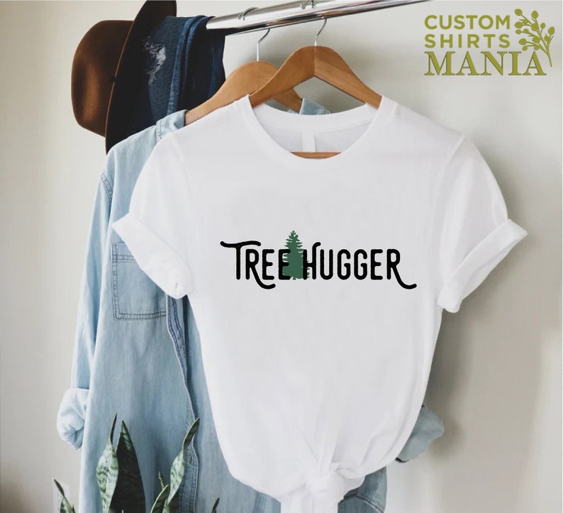May include: White t-shirt with a green tree graphic and the text "Tree Hugger" in black.