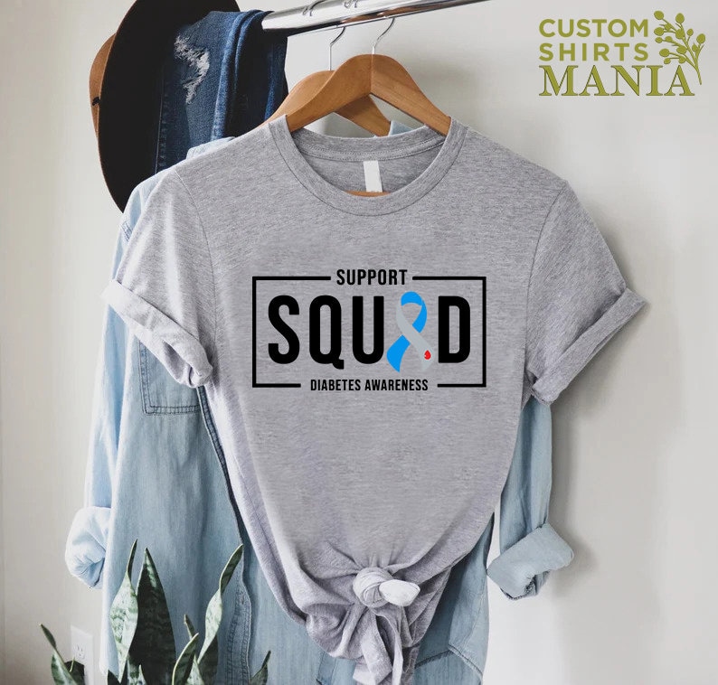 May include: Gray t-shirt with a black box that says "Support Squad" with a blue ribbon and the words "Diabetes Awareness" underneath.