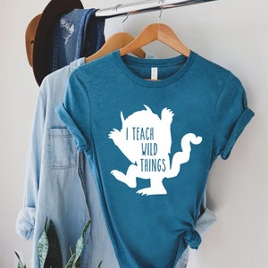 May include: A teal blue t-shirt with a white silhouette of a monster and the text "I teach wild things".