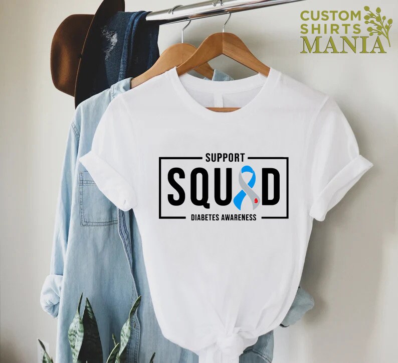 May include: White t-shirt with a black box that says "Support Squad" with a blue ribbon and the words "Diabetes Awareness" underneath.