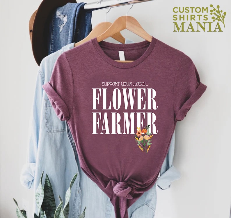 May include: A maroon t-shirt with white text that reads "Support your local Flower Farmer" and a small floral graphic.