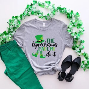 May include: A gray t-shirt with a green leprechaun graphic and the text "The Leprechauns Made Me Do It".