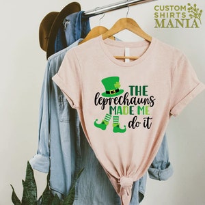 May include: A pink t-shirt with a green leprechaun graphic and the text "The Leprechauns Made Me Do It".
