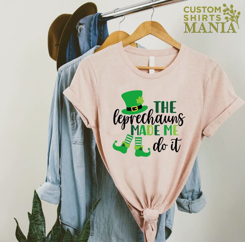 May include: A pink t-shirt with a green leprechaun graphic and the text "The Leprechauns Made Me Do It".