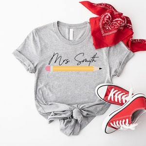 a t - shirt with a pencil on it next to a pair of sneakers