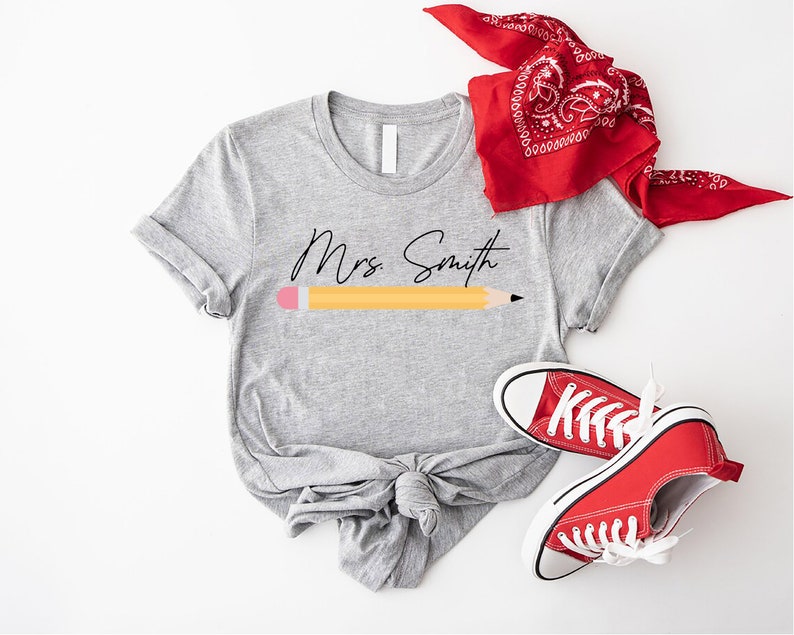 a t - shirt with a pencil on it next to a pair of sneakers