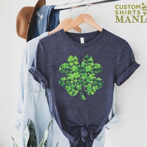 May include: A navy blue t-shirt with a green four-leaf clover design made of smaller clovers. The clover is a popular symbol of good luck and is often associated with St. Patrick's Day.