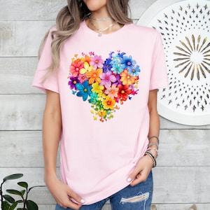 a woman wearing a pink t - shirt with a heart made of colorful flowers