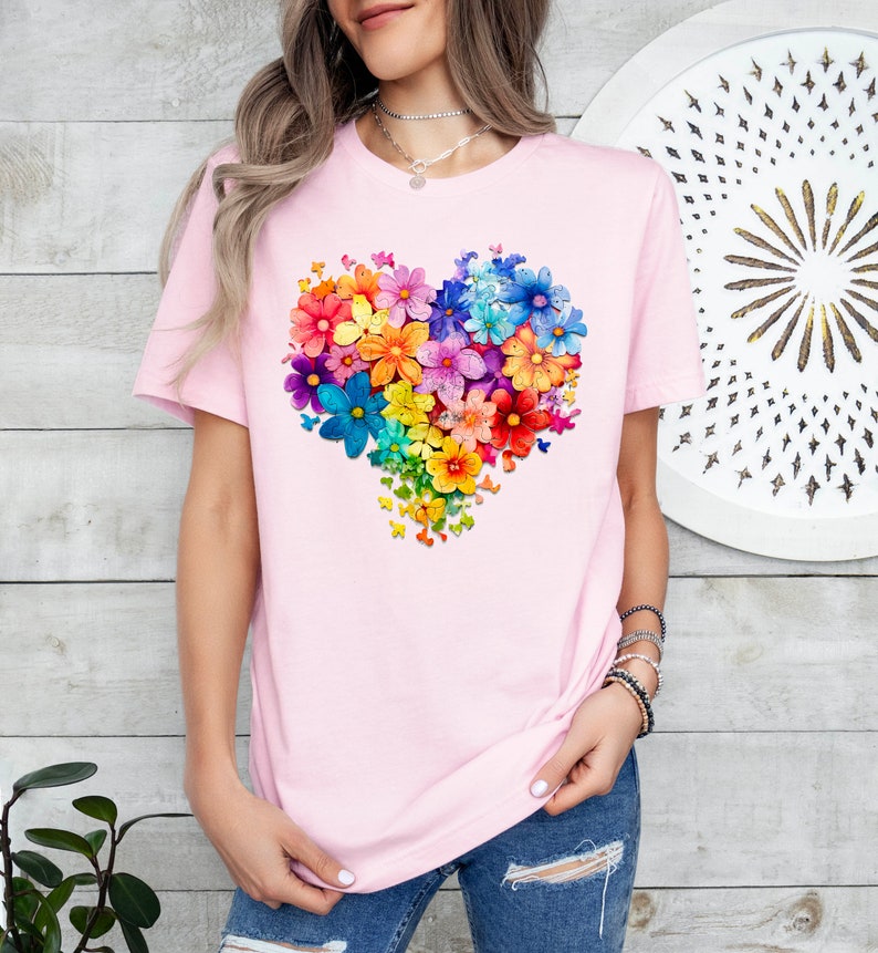 a woman wearing a pink t - shirt with a heart made of colorful flowers